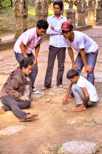 Young boys playing a game in the dirt, outside one of the temples at Angkor Wat in Cambodia